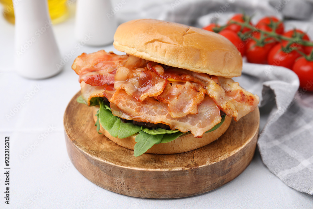 Delicious burger with bacon and greens on light table, closeup Delicious burger with bacon and greens on light table, closeup