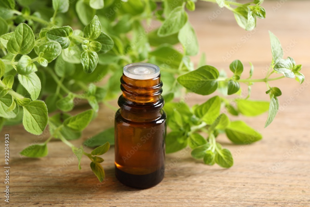 Essential oil in bottle and oregano twigs on wooden table, closeup Essential oil in bottle and oregano twigs on wooden table, closeup