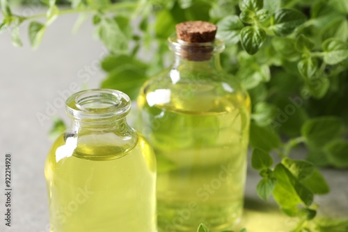 Essential oil in bottles and oregano twigs on light table, closeup