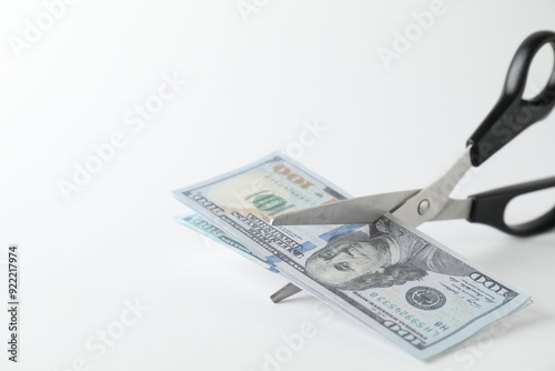 Budgeting. Cutting dollar banknotes with scissors on white background, closeup. Space for text