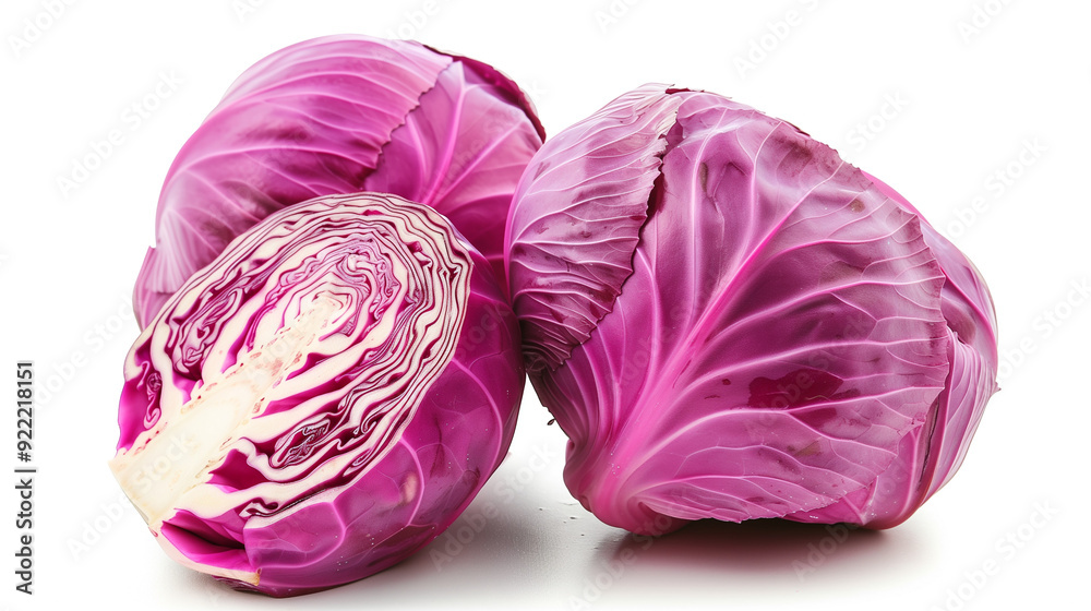 The image shows three heads of purple cabbage on a white background, one of which is cut open to reveal the clear layers The image shows three heads of purple cabbage on a white background, one of which is cut open to reveal the clear layers