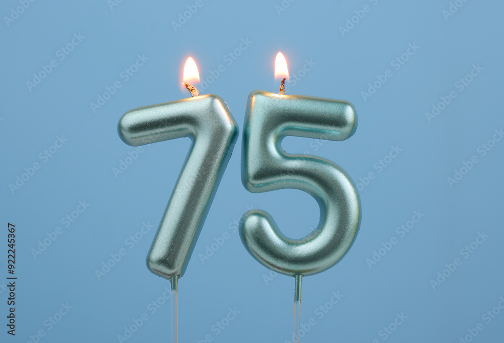 Burning blue birthday candles on blue background, number 75 Burning blue birthday candles on blue background, number 75