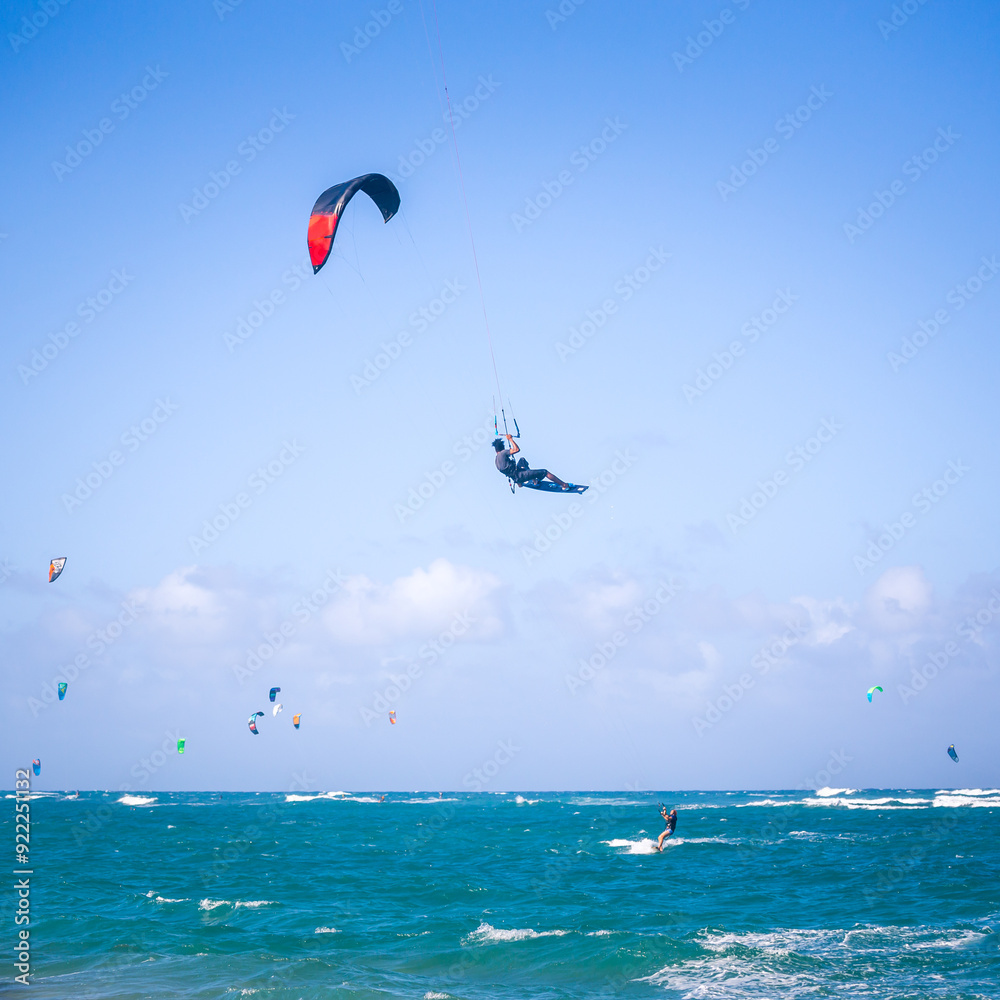 Kiteboarding. Fun in the ocean. Extreme Sport Kitesurfing. Kitesurfer jumping high in the air performing triks during kitesurfing session Kiteboarding. Fun in the ocean. Extreme Sport Kitesurfing. Kitesurfer jumping high in the air performing triks during kitesurfing session