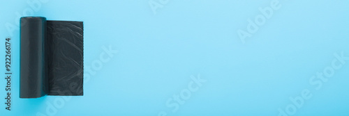 Εκτύπωση καμβά New dark black roll of plastic garbage bag on light blue table background