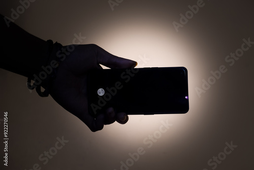 Hand Holding Smartphone in Dark with Backlight – Silhouette Concept