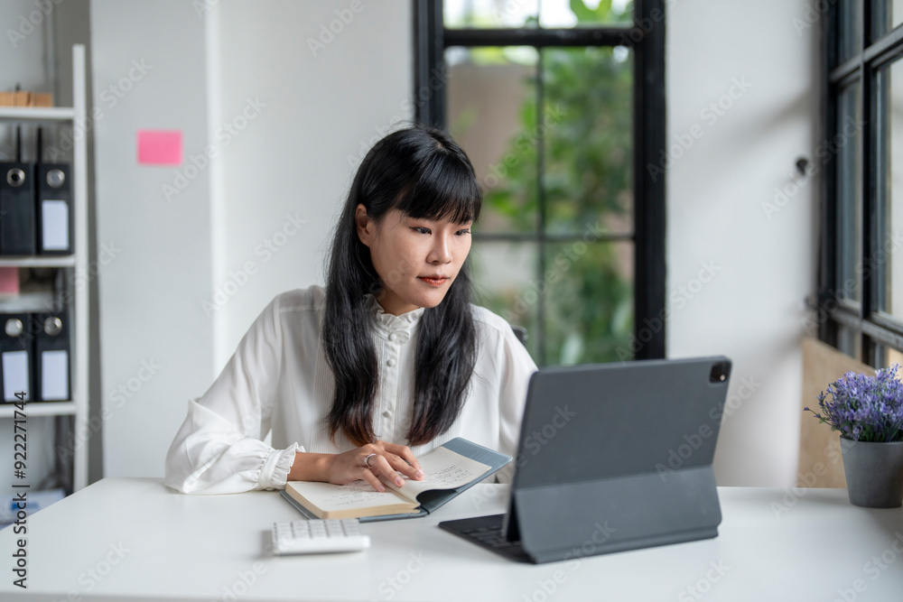 Businesswoman working from home office using digital tablet and taking notes Businesswoman working from home office using digital tablet and taking notes