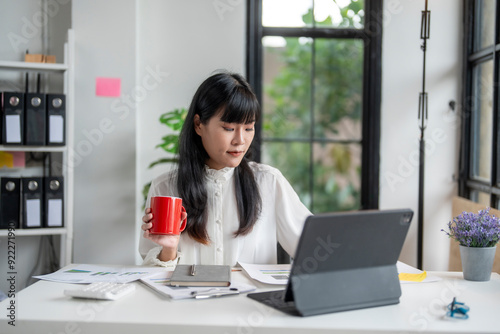 Asian accountant woman working with calculator and drinking coffee in office