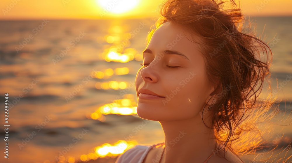 Delightful woman near the sea, eyes closed, enjoying the last rays of the sun during a stunning sunset Delightful woman near the sea, eyes closed, enjoying the last rays of the sun during a stunning sunset