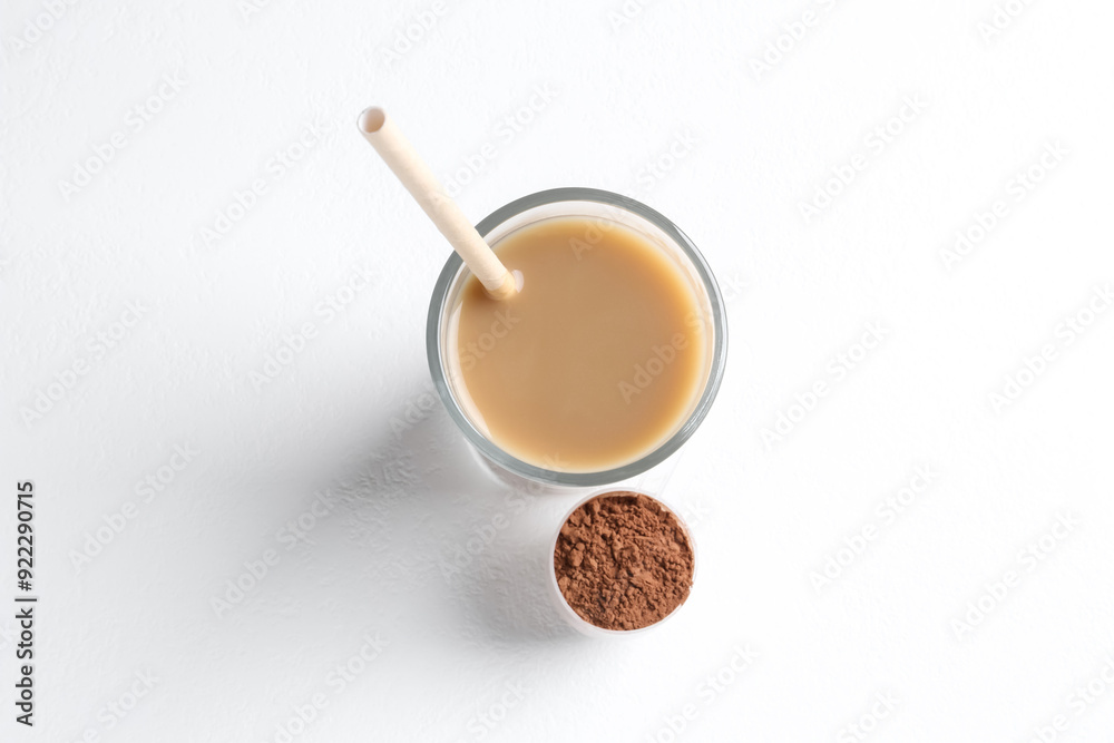 Delicious protein shake in glass and scoop with powder on white background, top view Delicious protein shake in glass and scoop with powder on white background, top view