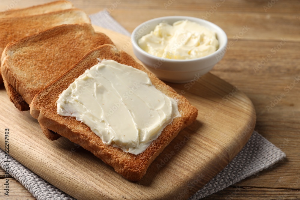 Delicious toasted bread slices with butter on wooden table Delicious toasted bread slices with butter on wooden table
