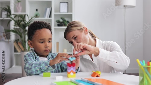 Assessment of mental development of children. Professional psychologist observes small multiracial boy playing with puzzle game, assessing his readiness for preschool. Exercises for kid with autism.