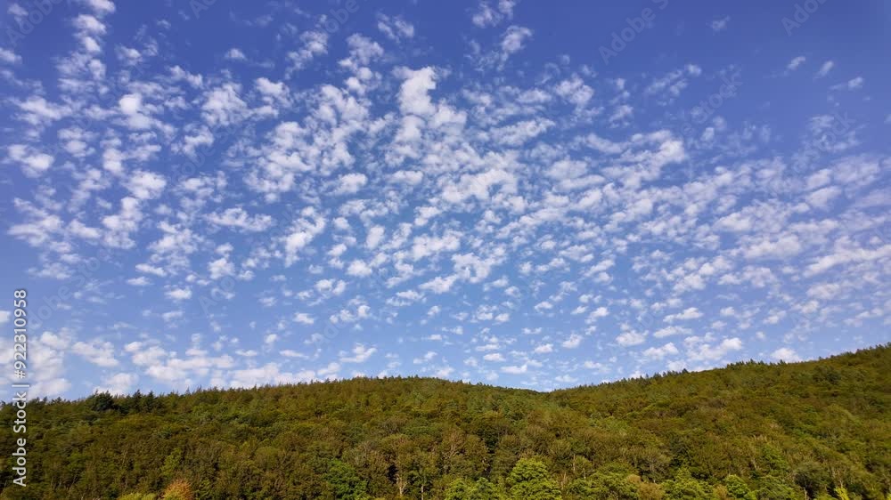 Evenly spared little clouds moving above the green hills. Magnificent nature, continuously developing white clouds against the blue sky. Relaxing or meditative nature near Lohr am Main, Germany. Evenly spared little clouds moving above the green hills. Magnificent nature, continuously developing white clouds against the blue sky. Relaxing or meditative nature near Lohr am Main, Germany.