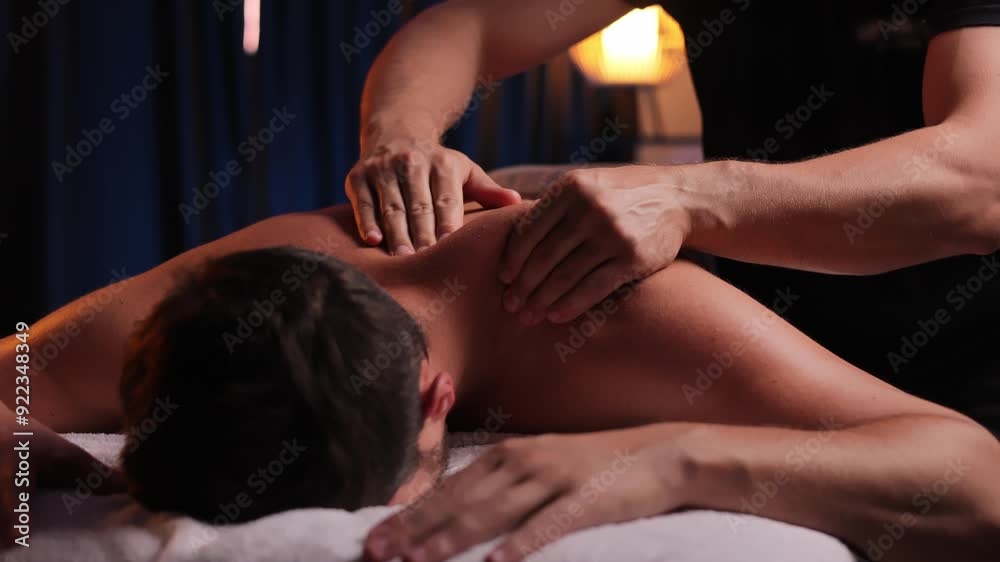 Physiotherapist massaging male patient with damaged shoulder muscle, treating sports injuries. Relaxing professional shoulder massage in cozy atmosphere, reboot on the weekend, end of difficult week.