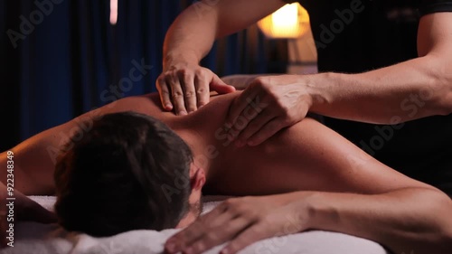 Physiotherapist massaging male patient with damaged shoulder muscle, treating sports injuries. Relaxing professional shoulder massage in cozy atmosphere, reboot on the weekend, end of difficult week.