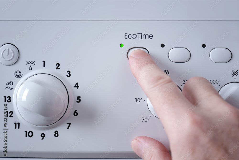 Close-up of a man's hand pressing the button for selecting the economical washing mode on the panel of the washing machine. Close-up of a man's hand pressing the button for selecting the economical washing mode on the panel of the washing machine.
