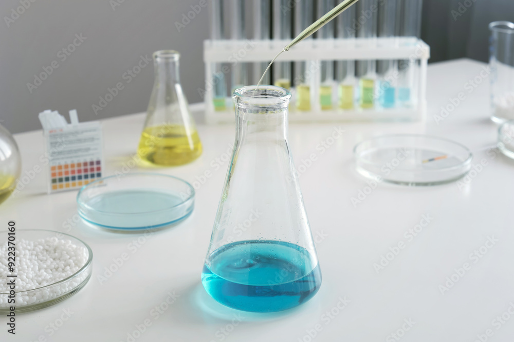 A scientist in a laboratory uses a pipette to analyze a colored liquid in test tubes. A scientist in a laboratory uses a pipette to analyze a colored liquid in test tubes.