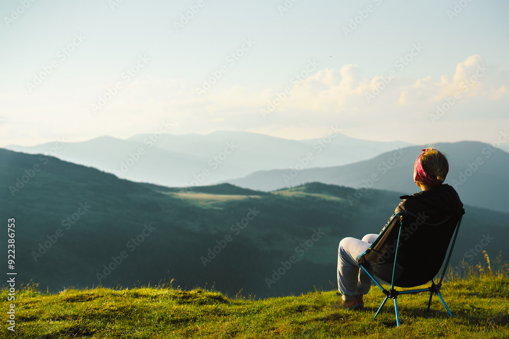 woman sit on tourist folding chair a hill overlooking a mountain range, against the background of mountains, tourism, hiking, nature of the Carpathian, vacation, outdoor activities, meditation woman sit on tourist folding chair a hill overlooking a mountain range, against the background of mountains, tourism, hiking, nature of the Carpathian, vacation, outdoor activities, meditation