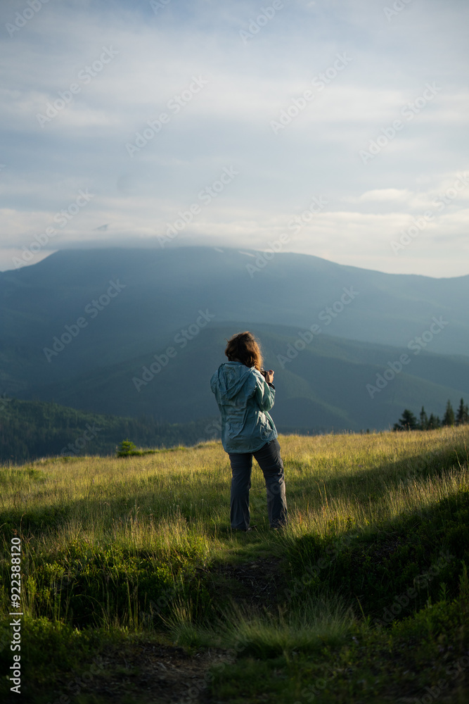 a woman with camera alone, smiling, happy, in the mountains, silhouettes of mountains on the background , in the forest, tourism, hiking, independence, overcoming fears, beauty of nature, solo hiking a woman with camera alone, smiling, happy, in the mountains, silhouettes of mountains on the background , in the forest, tourism, hiking, independence, overcoming fears, beauty of nature, solo hiking