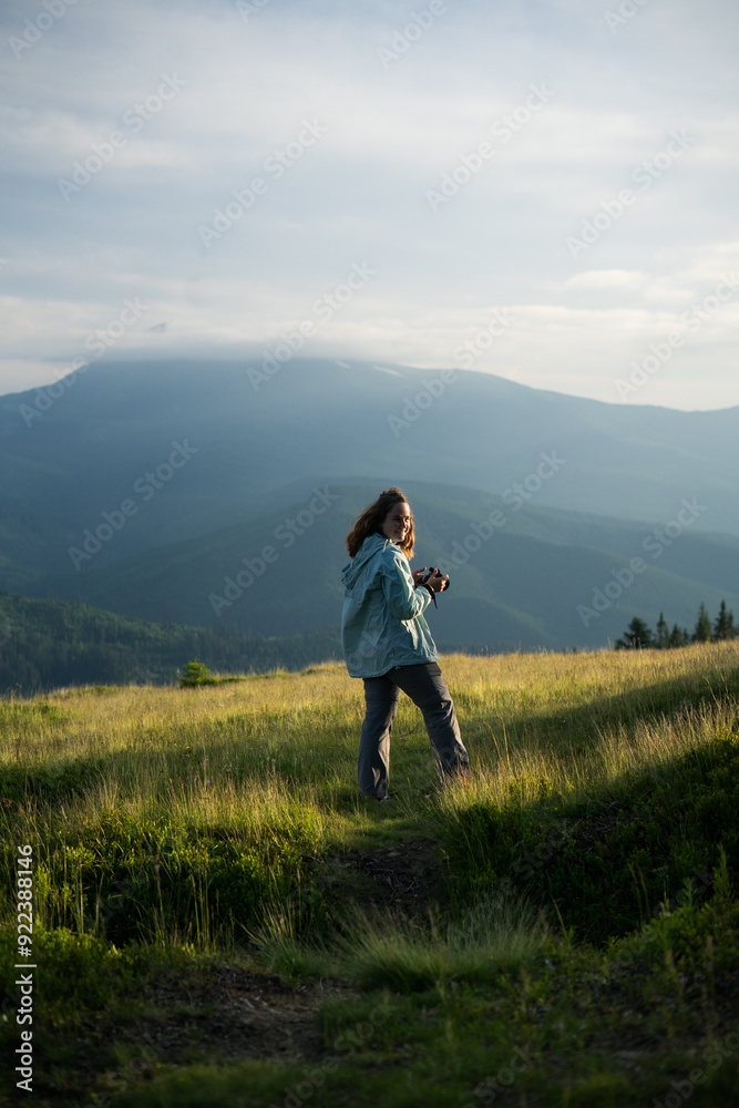 a woman with camera alone, smiling, happy, in the mountains, silhouettes of mountains on the background , in the forest, tourism, hiking, independence, overcoming fears, beauty of nature, solo hiking a woman with camera alone, smiling, happy, in the mountains, silhouettes of mountains on the background , in the forest, tourism, hiking, independence, overcoming fears, beauty of nature, solo hiking