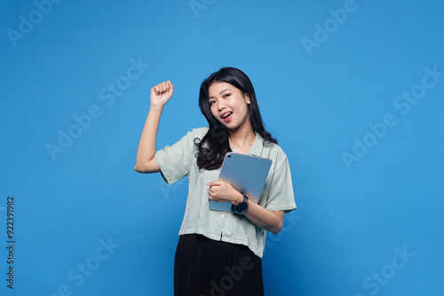 Happy success asian women holding Ipad isolated on blue background