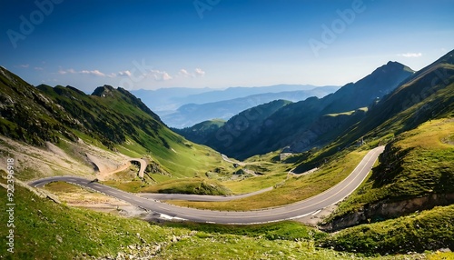 Serpentine road cuts through alpine valley, offering panoramic view of snow-capped peaks and lush green slopes