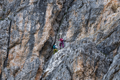 Two rock climbers climb a massive cliff on a sunny day. Extreme sports. photo