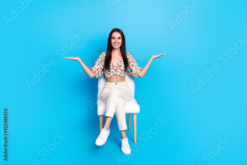 Full size photo of pretty young woman hold empty space vs wear top isolated on blue color background