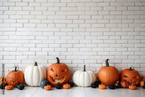 Row of orange and white Halloween pumpkins against a white brick wall indoors