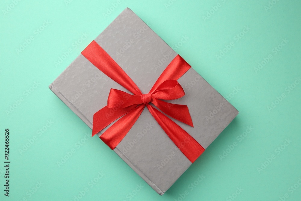 Book tied with red ribbon on green background, top view. Perfect gift Book tied with red ribbon on green background, top view. Perfect gift