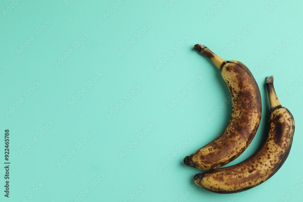 Overripe bananas with dark spots on turquoise background, top view. Space for text Overripe bananas with dark spots on turquoise background, top view. Space for text