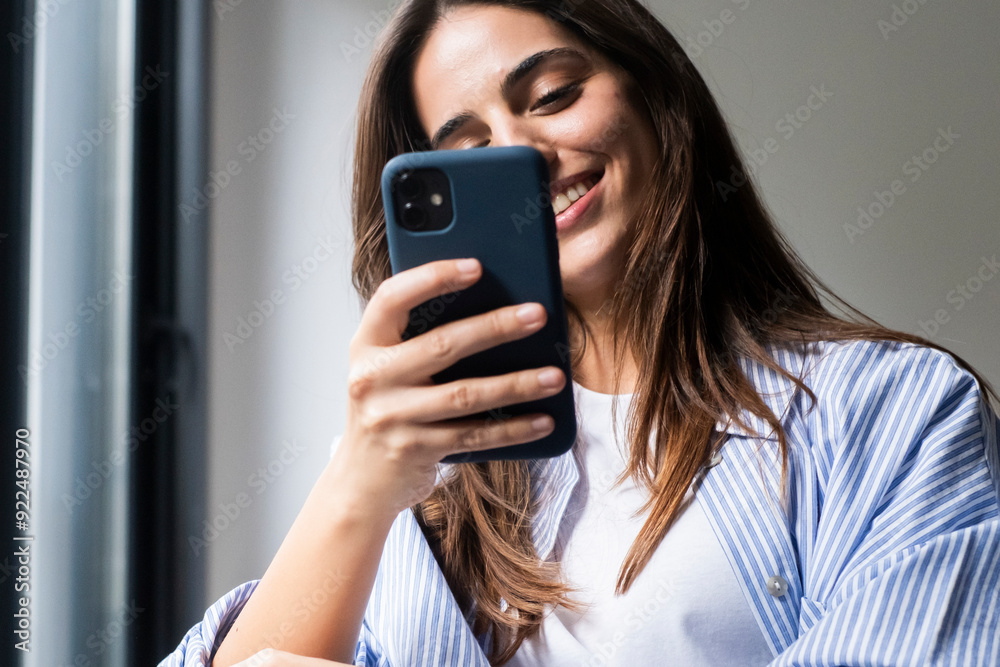Happy pleasant millennial woman relaxing on comfortable couch, holding smartphone in hands. Smiling young lady chatting in social networks, watching funny videos, using mobile applications at home. Happy pleasant millennial woman relaxing on comfortable couch, holding smartphone in hands. Smiling young lady chatting in social networks, watching funny videos, using mobile applications at home.