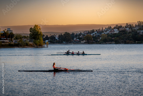 Silhouette of people enjoying rowing on Saint Roque Lake in Villa Carlos Paz at sunset