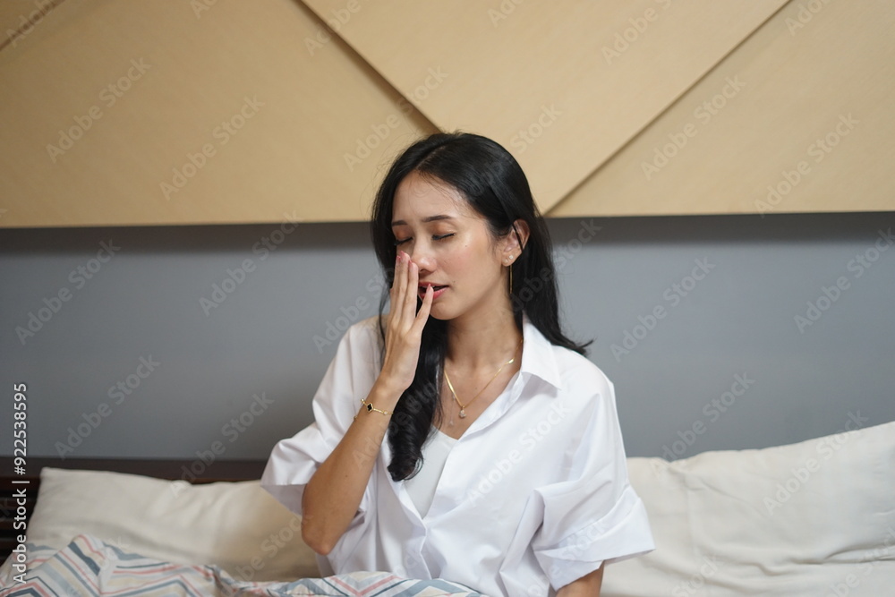 woman waking up in bed yawning and grimacing early morning after sleep sitting in bedroom woman waking up in bed yawning and grimacing early morning after sleep sitting in bedroom