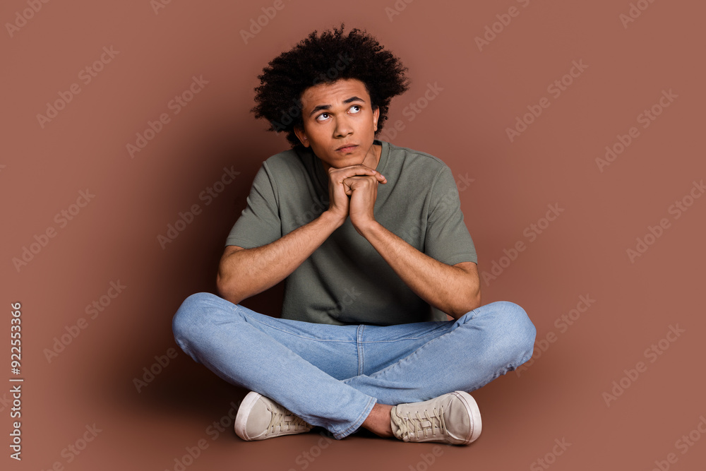 Full size photo of nice young guy look thoughtful empty space wear trendy khaki outfit isolated on brown color background Full size photo of nice young guy look thoughtful empty space wear trendy khaki outfit isolated on brown color background