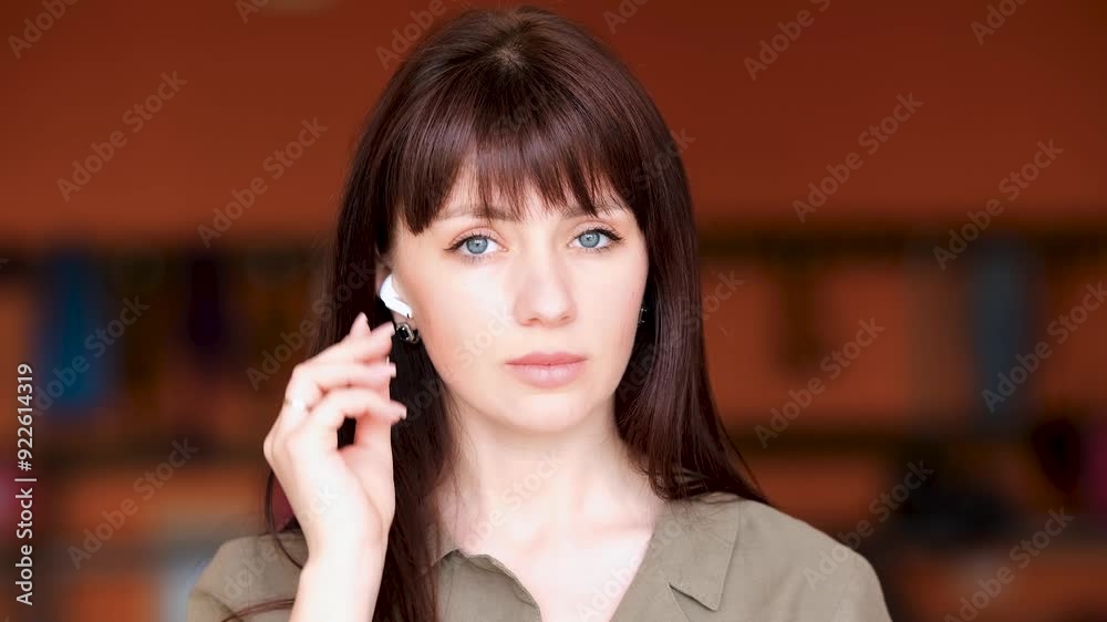 Portrait of a beautiful long-haired girl putting on white wireless headphones. Portrait of a beautiful long-haired girl putting on white wireless headphones.