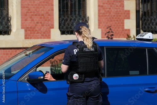 Female police officer checks the driver's ID of a blue taxi photo