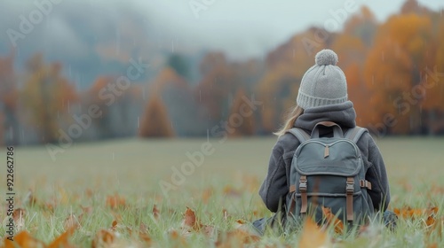Woman Sitting in Grass With Backpack Overlooking Mountain Landscape at Dusk