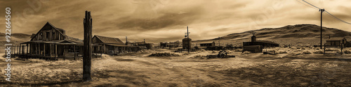 A haunting sepia-toned banner vision of a forgotten ghost town, its weathered structures silent sentinels of the past. photo