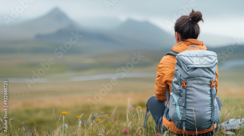 Woman Sitting in Grass With Backpack Overlooking Mountain Landscape at Dusk