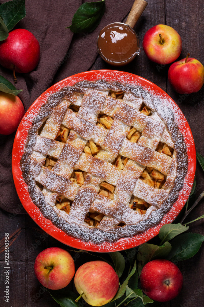 Traditional holiday apple pie with cinnamon and cardamom in a ceramic form, apples and apple branches.