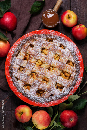 Obraz na płótnie Traditional holiday apple pie with cinnamon and cardamom in a ceramic form, apples and apple branches. w salonie