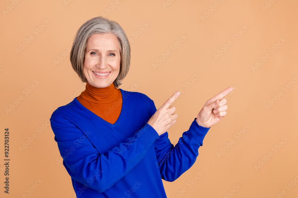 Photo portrait of nice senior woman point empty space wear trendy blue outfit isolated on beige color background Photo portrait of nice senior woman point empty space wear trendy blue outfit isolated on beige color background