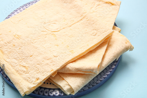 Plate with fresh thin lavash on blue background photo
