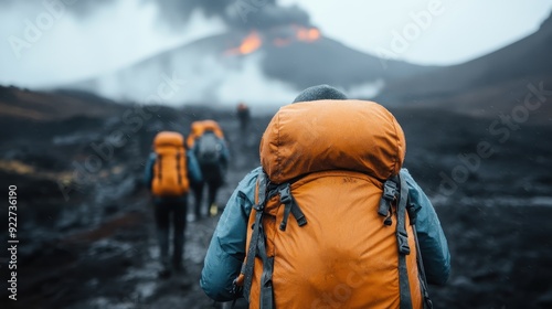 Several explorers equipped with orange backpacks trek on black volcanic terrain, heading towards an active volcano emitting smoke and surrounded by ominous skies.