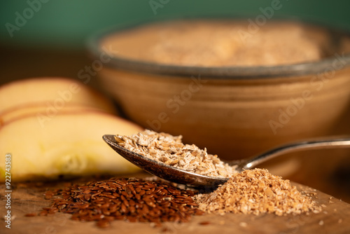 A spoon with cereal, in the background a bowl and apples