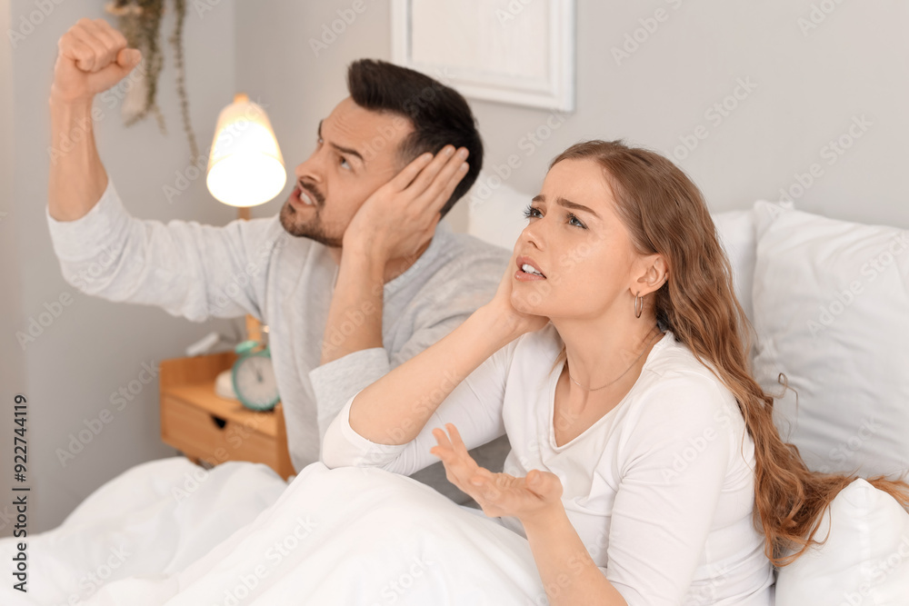 Young couple suffering from loud neighbours in bedroom Young couple suffering from loud neighbours in bedroom
