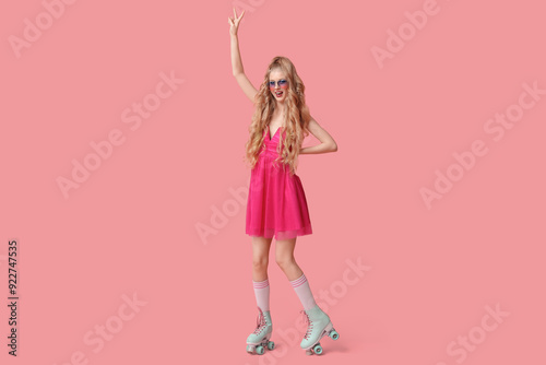 Beautiful young woman in vintage roller skates on pink background