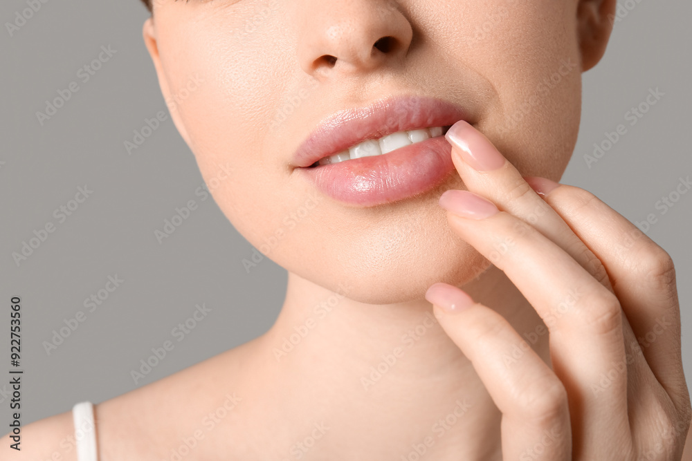 Beautiful young woman applying lip balm on grey background, closeup Beautiful young woman applying lip balm on grey background, closeup