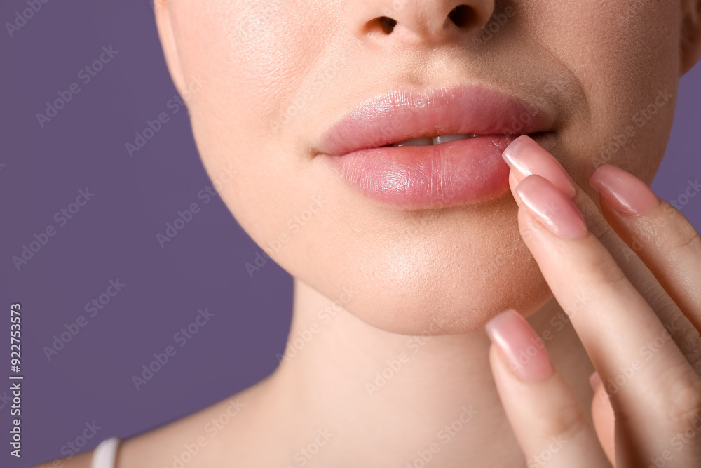 Obraz premium Beautiful young woman touching lips with filler on purple background, closeup
