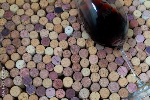 Glass of red wine on background of wine corks close-up